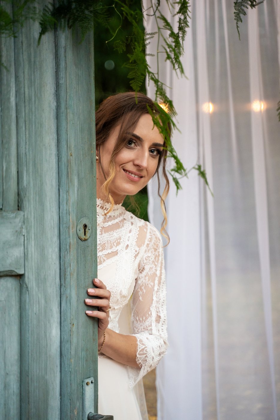 Panna młoda z uśmiechem wygląda zza drzwi — ślub Magda i Bernard