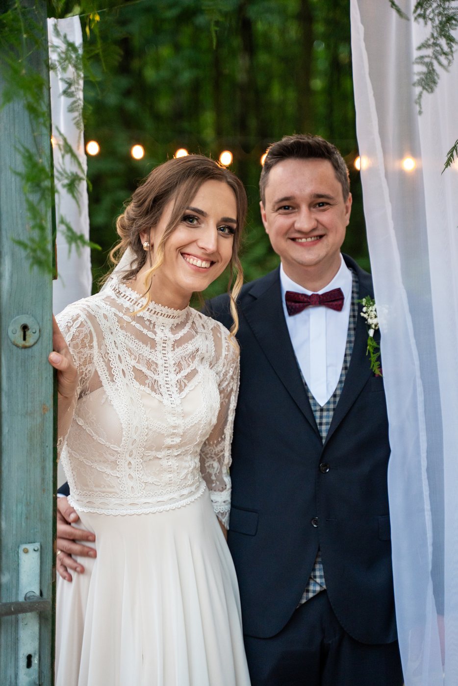 Para młoda w drzwiach ozdobionych gipsówką — ślub Magda i Bernard