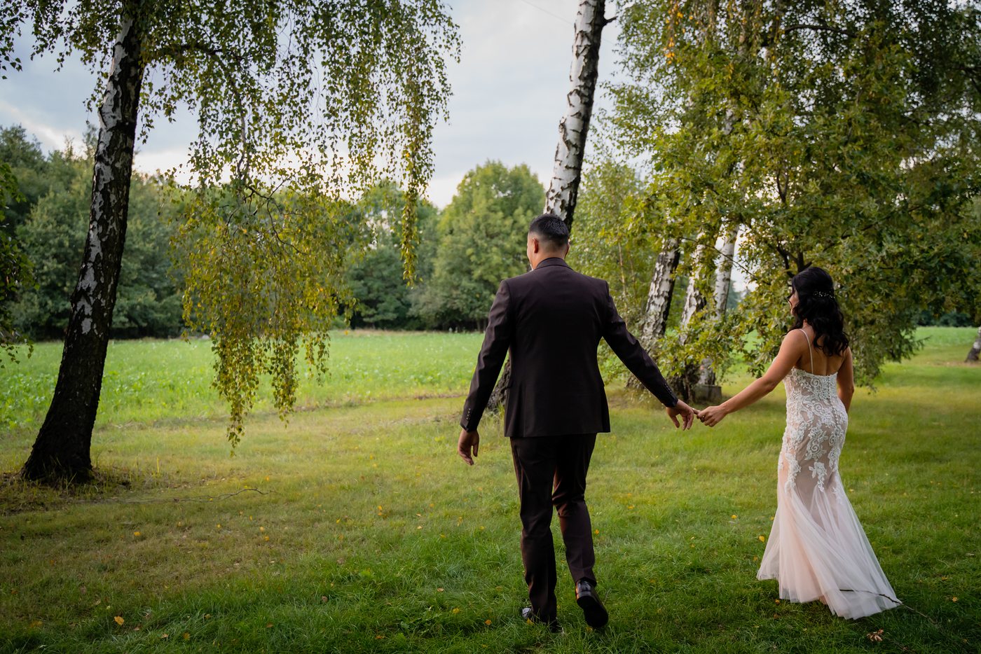 Para młoda idzie trzymając się za ręce między brzozami — ślub Malwina i Jan